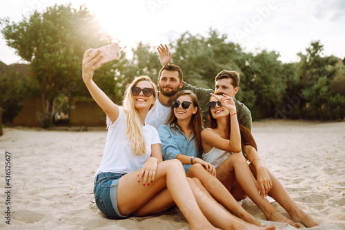 Group of people doing selfie with phone at the beach. Young friends enjoy summer party together. People, lifestyle, travel, nature and vacations concept.