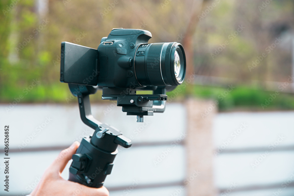 Man holding a gimbal stabilizer outdoor. Man holding a gimbal stabilizer outdoor.