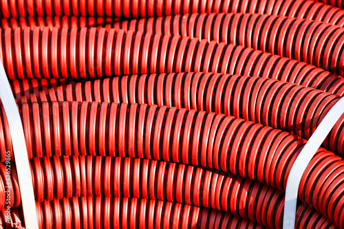 Red plastic corrugated hose for insulation and laying of wires and cable close-up. Background for an electrical component supplier with copy space