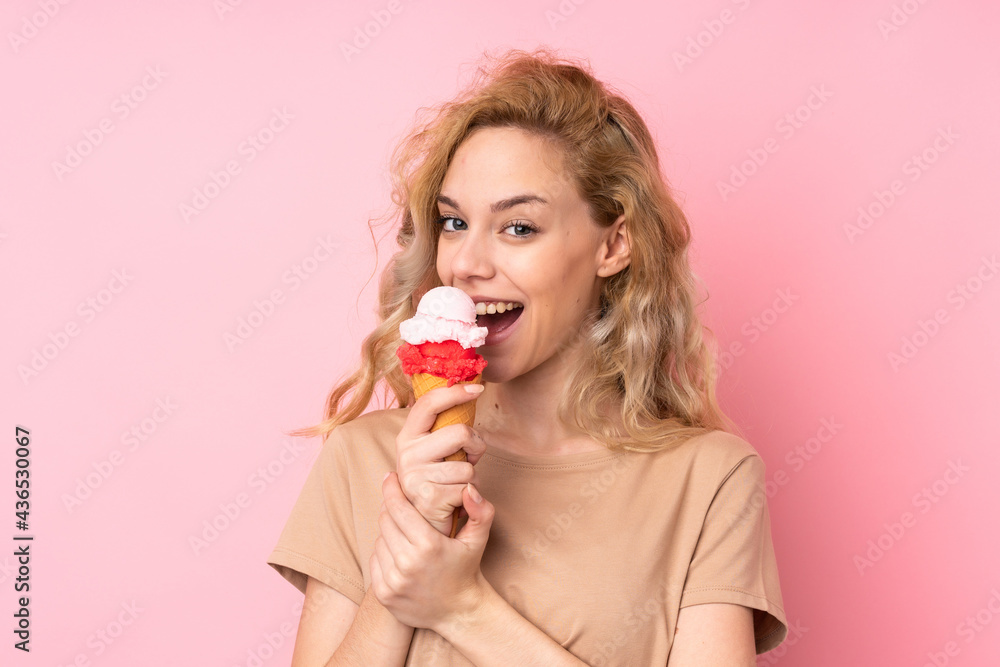 Young blonde woman holding a cornet ice cream isolated on pink background Young blonde woman holding a cornet ice cream isolated on pink background