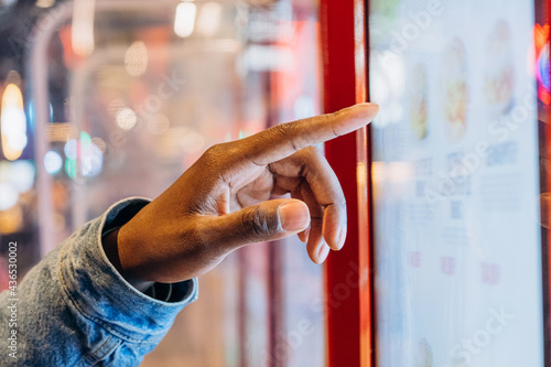Fotografie A close-up African finger selects a burger on an electronic touch screen at a se