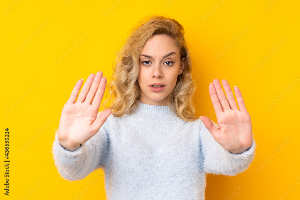 Young blonde woman isolated on yellow background making stop gesture and disappointed Young blonde woman isolated on yellow background making stop gesture and disappointed