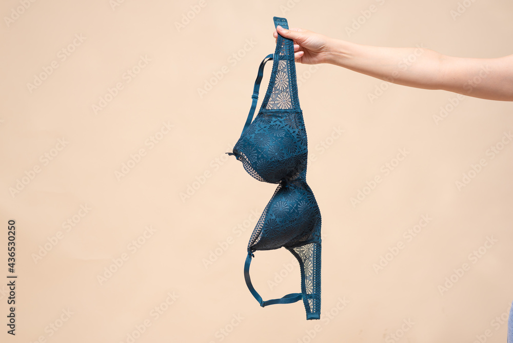 Woman is showing a new bra in the hand. Choosing a new bra concept. - obrazy, fototapety, plakaty 