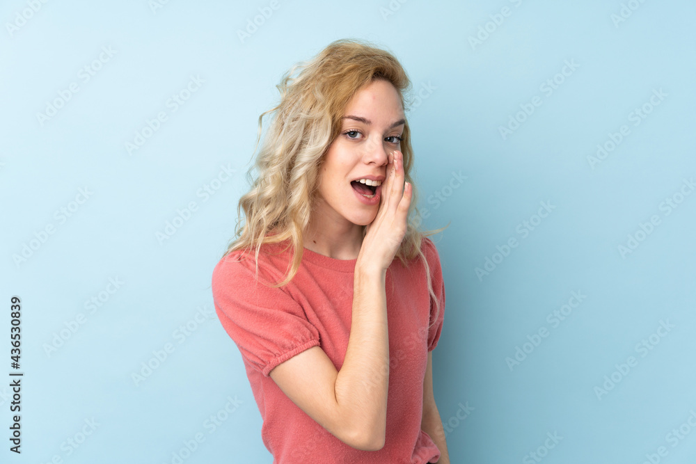 Young blonde woman isolated on blue background whispering something Young blonde woman isolated on blue background whispering something