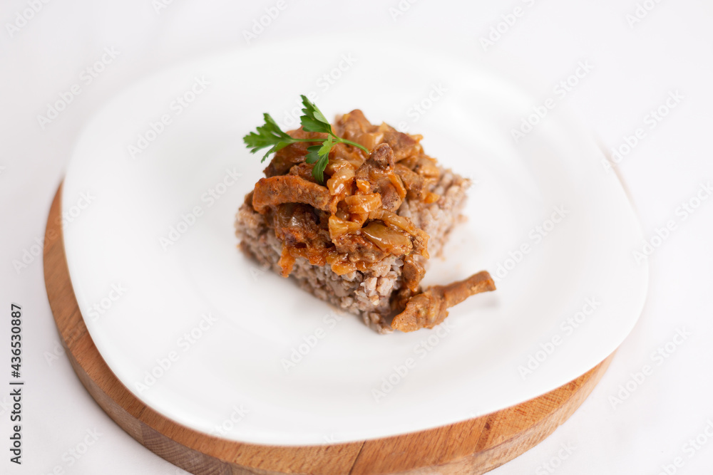 dish of buckwheat porridge with meat close-up on white background