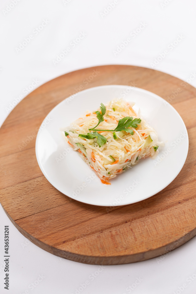 Fresh cabbage carrot and cucumber salad on white plate