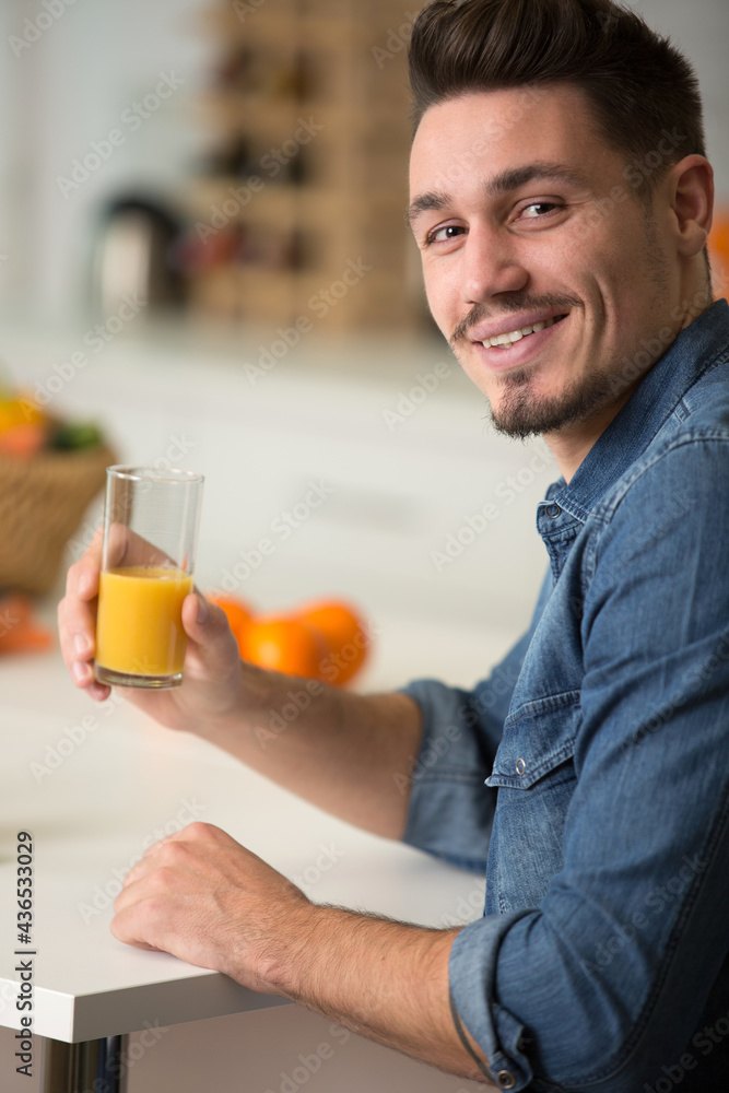 young man holding glass of orange juice young man holding glass of orange juice
