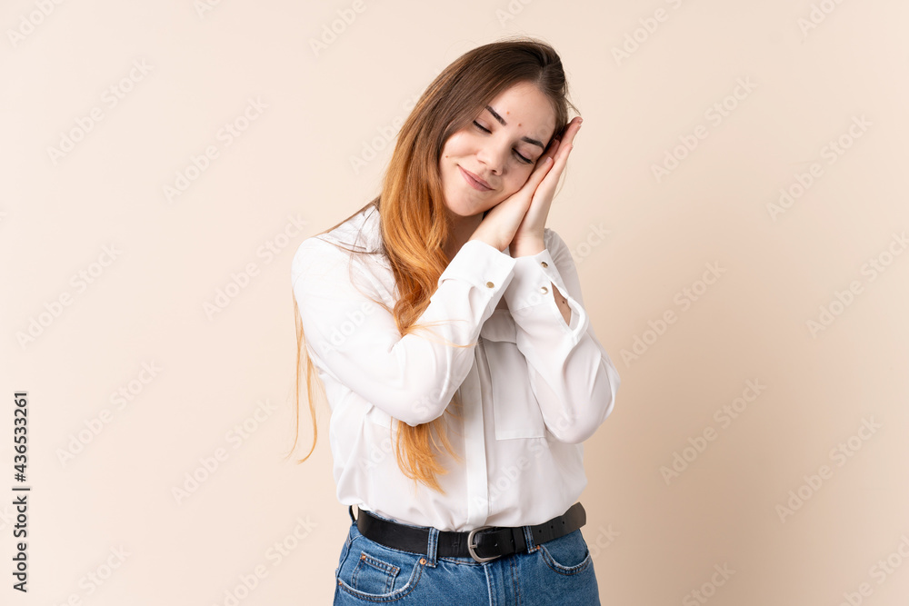 Young caucasian woman isolated on beige background making sleep gesture in dorable expression Young caucasian woman isolated on beige background making sleep gesture in dorable expression