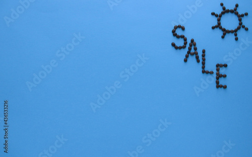 The word sale and the sun made from coffee beans In the upper right corner. Banner. On a blue paper background. Copy space. 