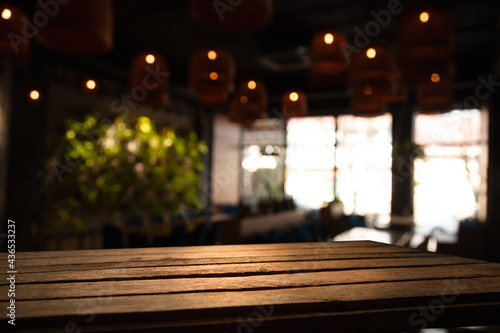 empty wooden table on blurred light gold bokeh of cafe restaurant window on dark background, place for your products on the table