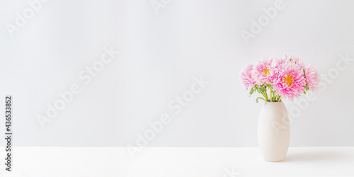 Pink flowers in a vase on a light background at home interior. Modern interior design