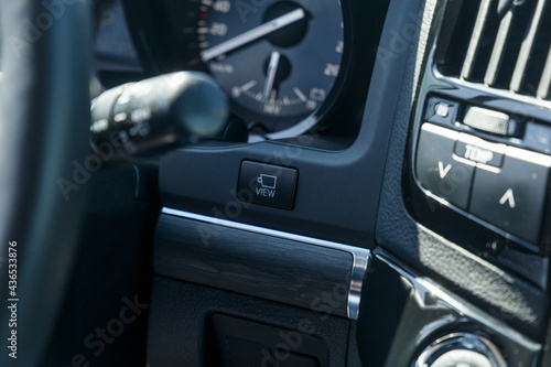 Button for switching the car's all-round view cameras. Modern car interior. Soft focus. Modern car illuminated dashboard. Luxurious car instrument cluster. Close up shot of automobile instrument panel