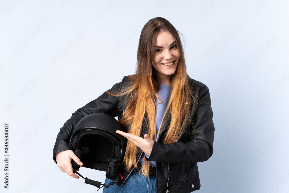 Woman with a motorcycle helmet extending hands to the side for inviting to come Woman with a motorcycle helmet extending hands to the side for inviting to come