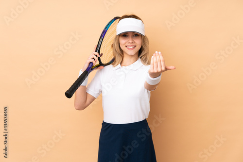 Teenager Russian girl isolated on beige background playing tennis and doing coming gesture © luismolinero