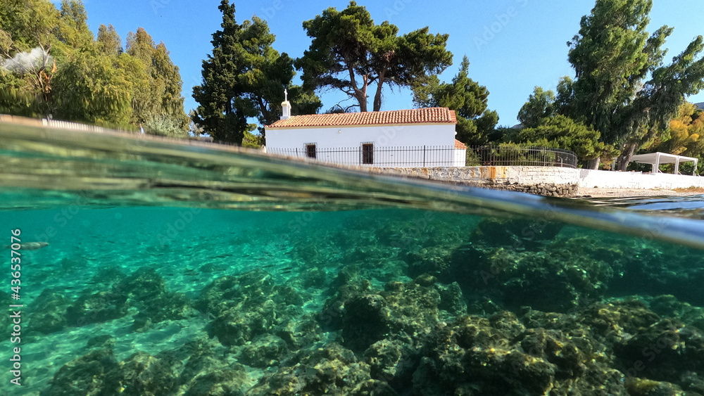 Underwater split photo of picturesque white washed chapel built by the sea in Greek island sandy beach