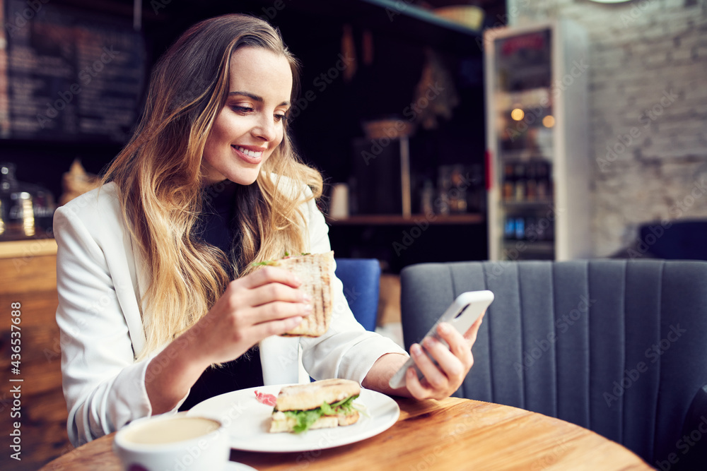 Beautiful woman eating breakfast at cafe using smartphone Beautiful woman eating breakfast at cafe using smartphone