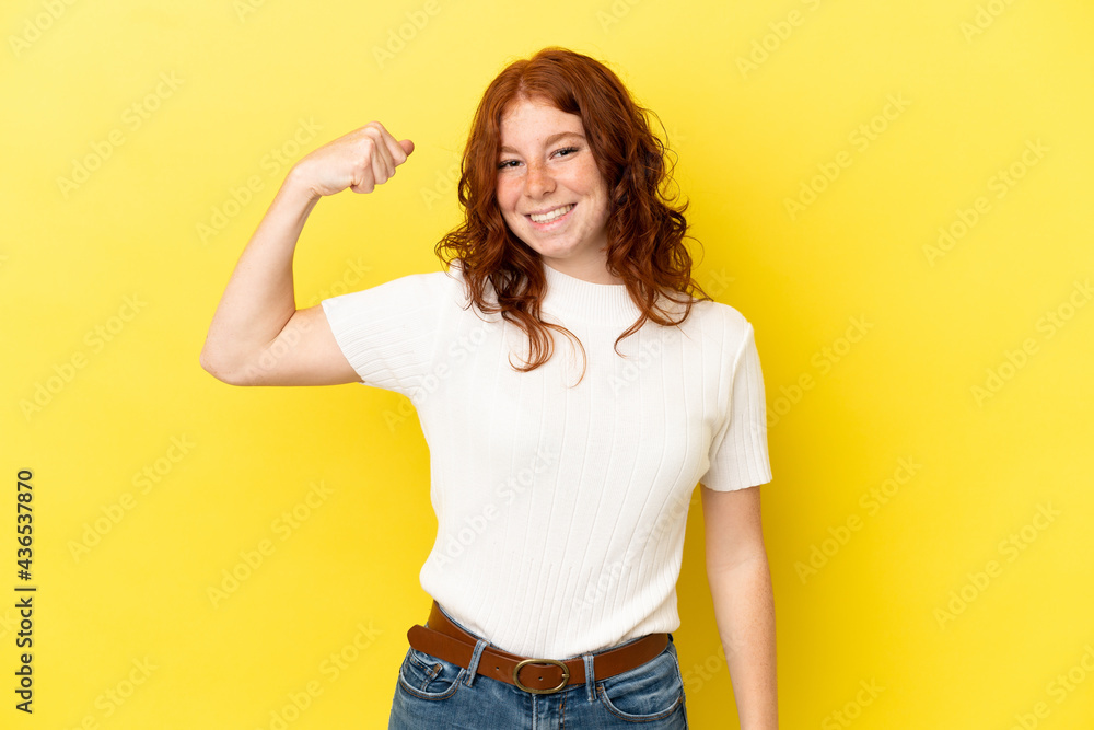 Teenager reddish woman isolated on yellow background doing strong gesture Teenager reddish woman isolated on yellow background doing strong gesture