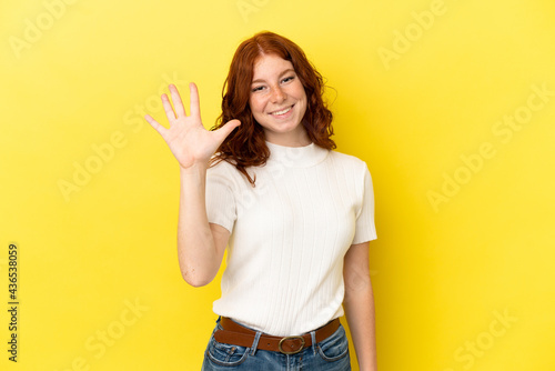 Teenager reddish woman isolated on yellow background counting five with fingers