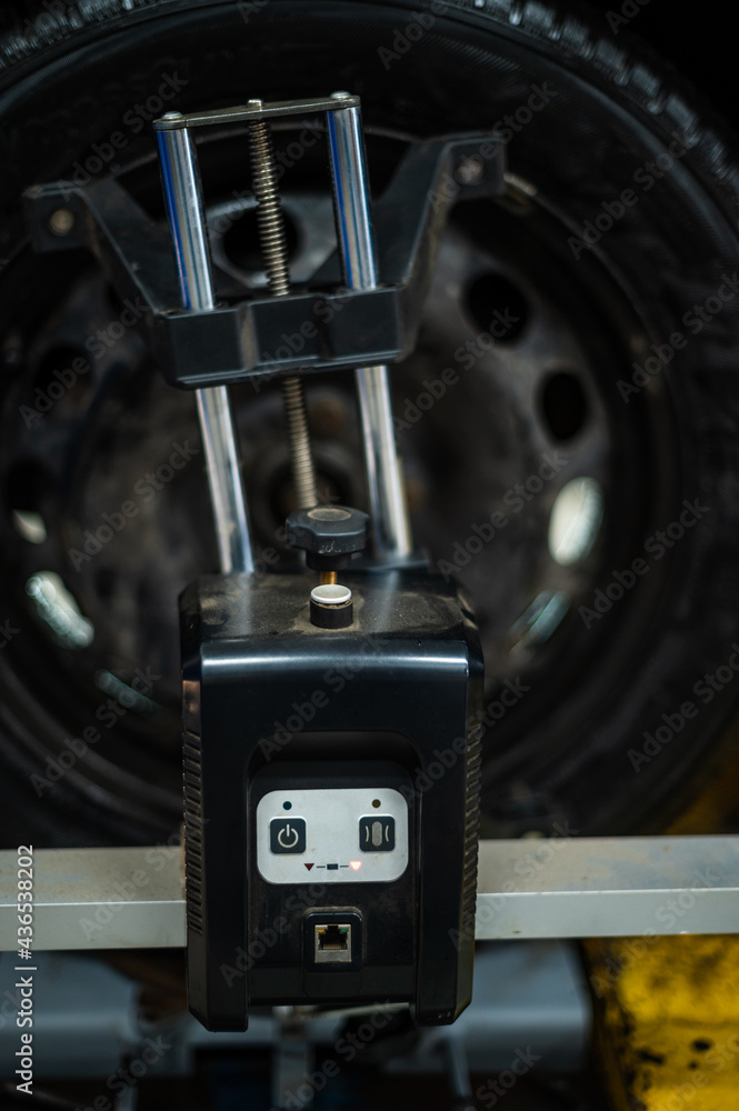 Fototapeta premium Close-up of a tire clamped by a leveler that passes the automatic alignment of the wheels in the garage, garage and tools for the mechanic.