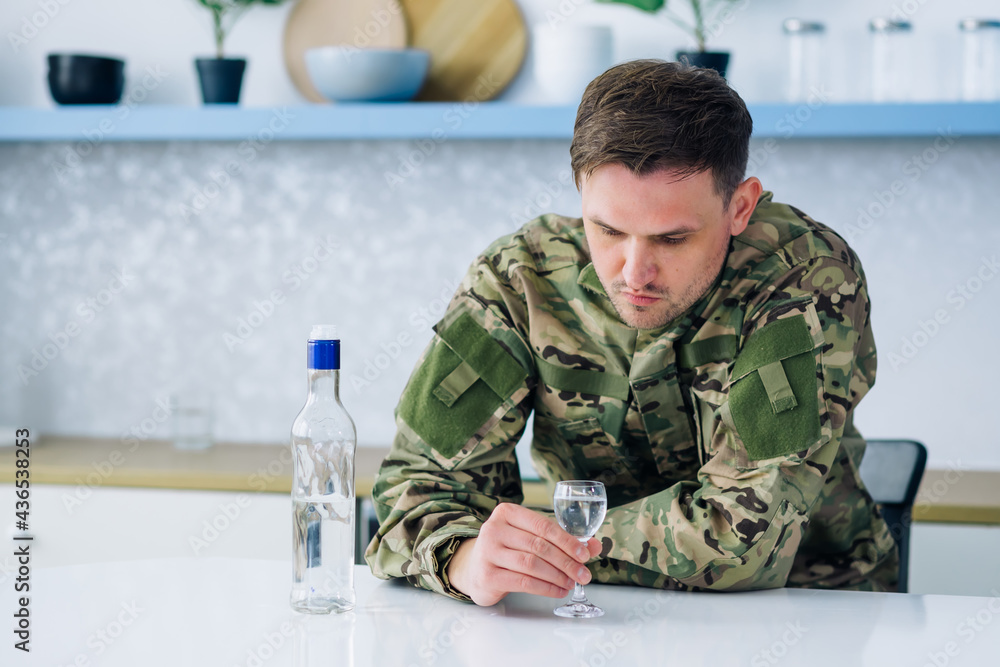 Fototapeta premium Young male civilian soldier sitting at home at kitchen bar with