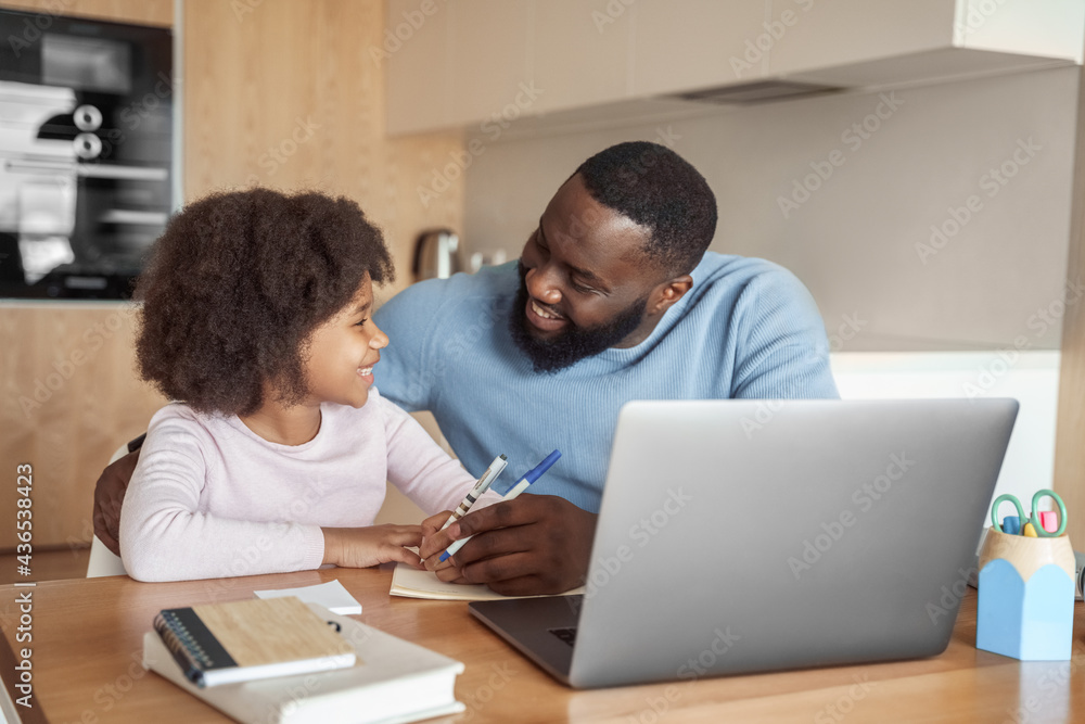 Happy african american family doing home task. Caring father help little daughter with school subject homework. Homeschooling conducted by parent, distant e-study and e-learning concept Happy african american family doing home task. Caring father help little daughter with school subject homework. Homeschooling conducted by parent, distant e-study and e-learning concept