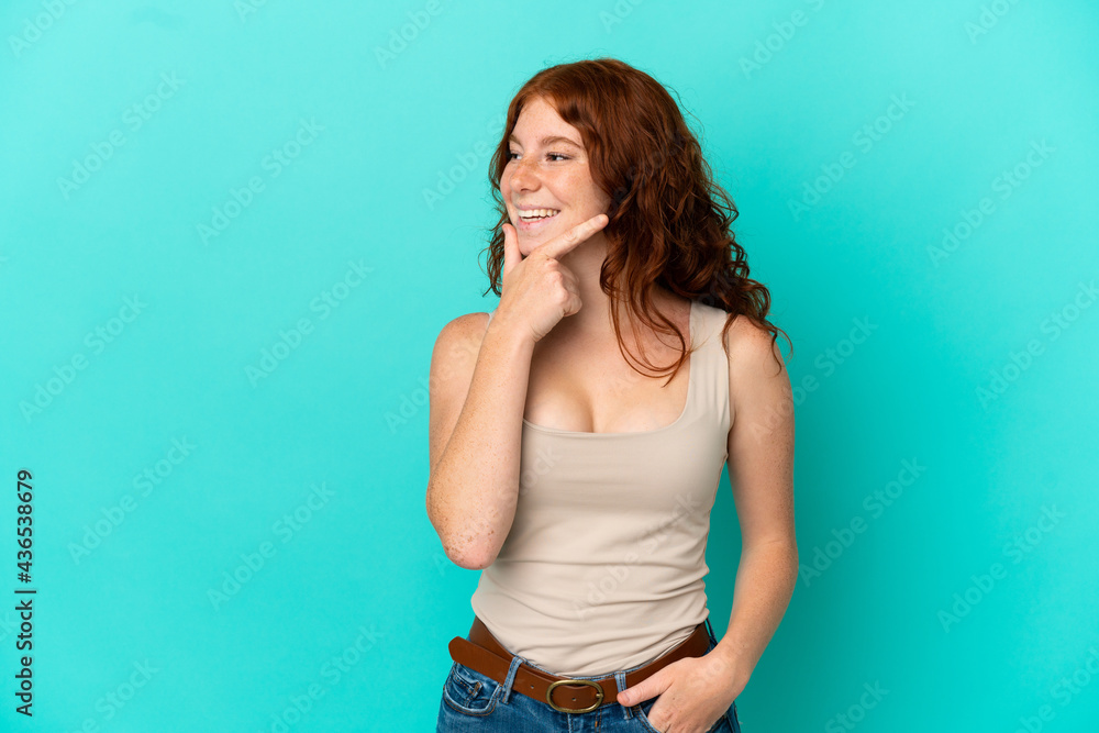 Teenager reddish woman isolated on blue background looking to the side and smiling Teenager reddish woman isolated on blue background looking to the side and smiling