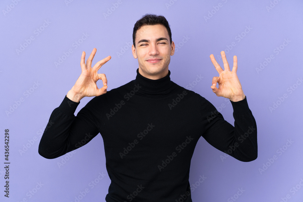 Young caucasian handsome man with turtleneck sweater isolated on purple background in zen pose Young caucasian handsome man with turtleneck sweater isolated on purple background in zen pose
