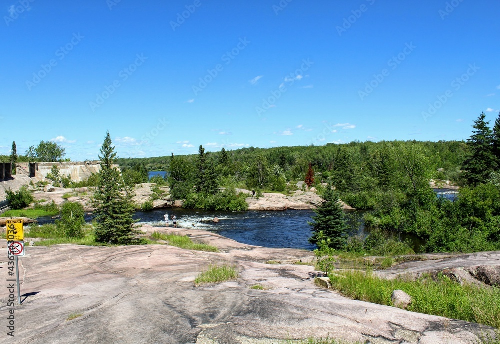 Fototapeta premium Pinawa Dam: Panoramic view of the river, stone bank and forest
