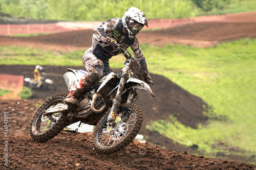 Motorcycle racer on a turn. It rained. Rider gear and motorcycle in the dirt.