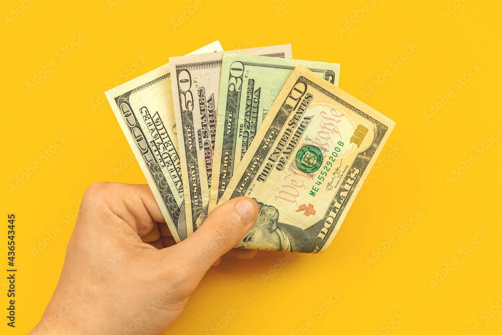 Man with his salary in hand, counting and showing salary concept, yellow background and office desk photo