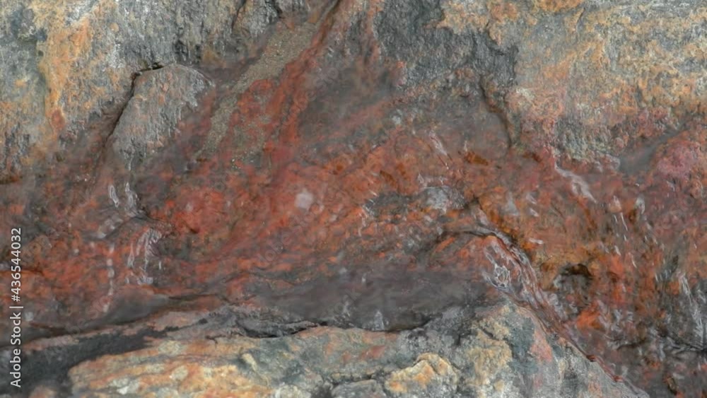 Water flowing over red granite rockbed in slowmotion Water flowing over red granite rockbed in slowmotion