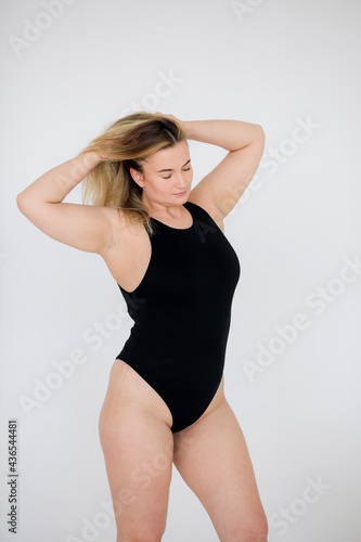 Beautiful overweight woman in black swimsuit on grey background © kalinichenkod