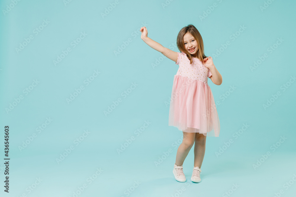 Full size body length little fun cute kid girl 5-6 years old wears pink dress dancing isolated on pastel blue color background child studio portrait. Mother's Day love family people lifestyle concept.