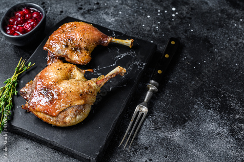 Roasted duck leg confit with cranberrie sauce. Black background. top view. Copy space photo