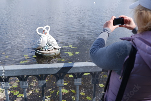 A girl in a white cap takes pictures of the water landscape with a camera. St. Veronica's Day Photographer's Day . photo