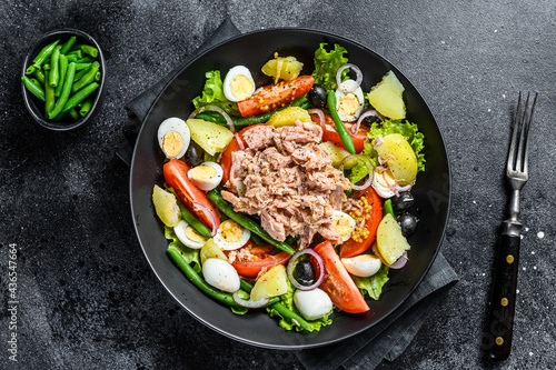Tuna salad  nicoise with vegetables, eggs and anchovies in a plate. Black background. top view