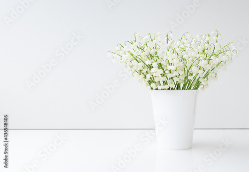 spring flowers lily of the valley in white vase on white background. copy space. minimalism