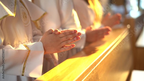 Hands of children folded in prayer during the First Holy Communion photo