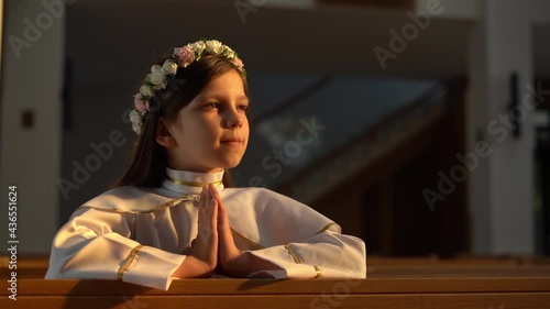The girl prays in church during her First Holy Communion photo