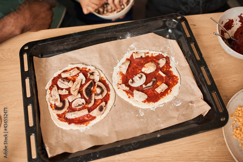 Vegan pizza with mushrooms laying at the baking sheet and preparing for the baking photo