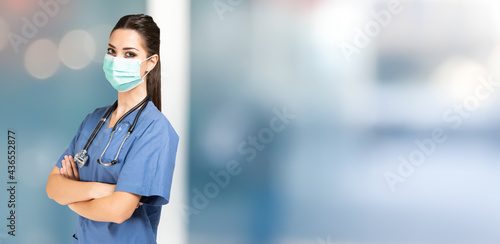 Masked female nurse portrait, covid coronavirus mask. Wide background with large copy-space