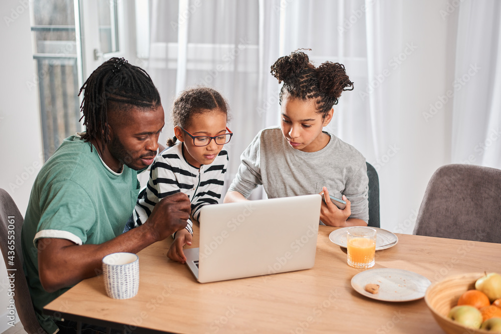 Sisters watching cartoons at the laptop wit their father Sisters watching cartoons at the laptop wit their father