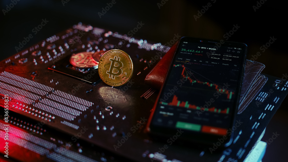 Smartphone with bitcoin and crypto stock chart interface on red blue illuminated motherboard, finance and crypto coin concept