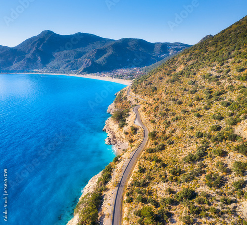 Fototapeta Naklejka Na Ścianę i Meble -  Aerial view of mountain road near blue sea, sandy beach at sunset in summer. Oludeniz, Turkey. Top view of road, trees, clear water, mountain. Beautiful landscape with highway, rocks and sea coast	