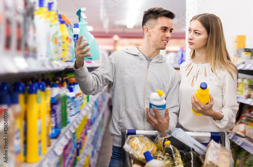 Nice couple doing shopping together, choosing household detergents in store