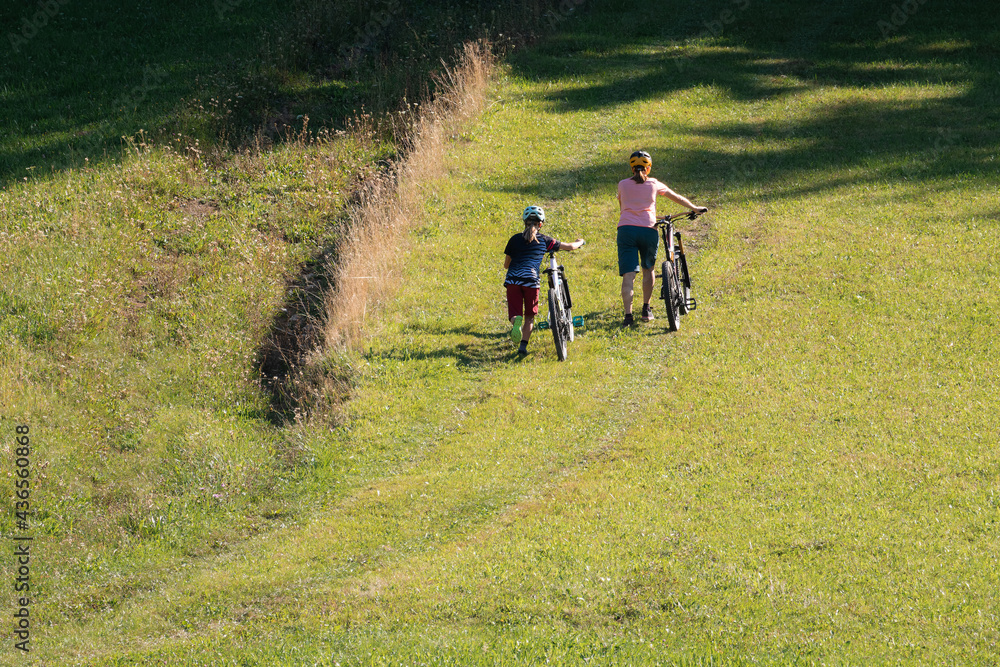 Fototapeta premium Two girls on mtb bikes. Mother and daughter riding on a trail.