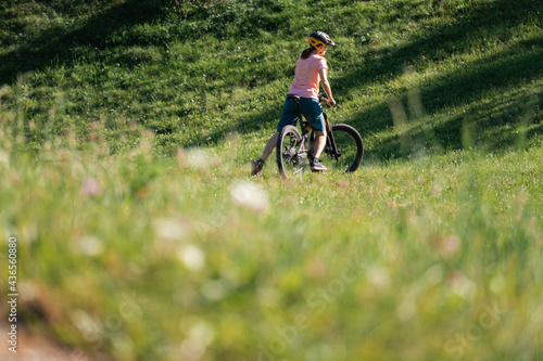 Woman riding mountain bike on a green meadow in summer.
