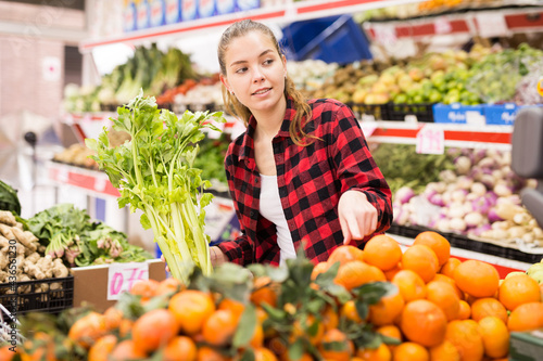 Friendly female shop assistant is helping to buy oranges at supermarket