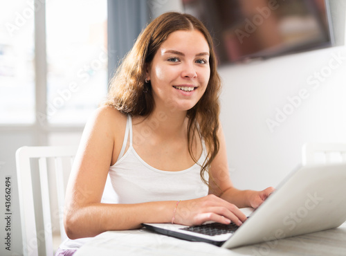 Young girl student with laptop working at home