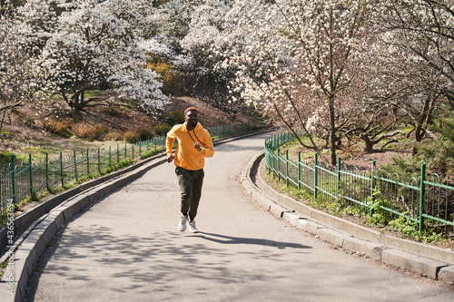 Happy young man jogging in spring park in morning
